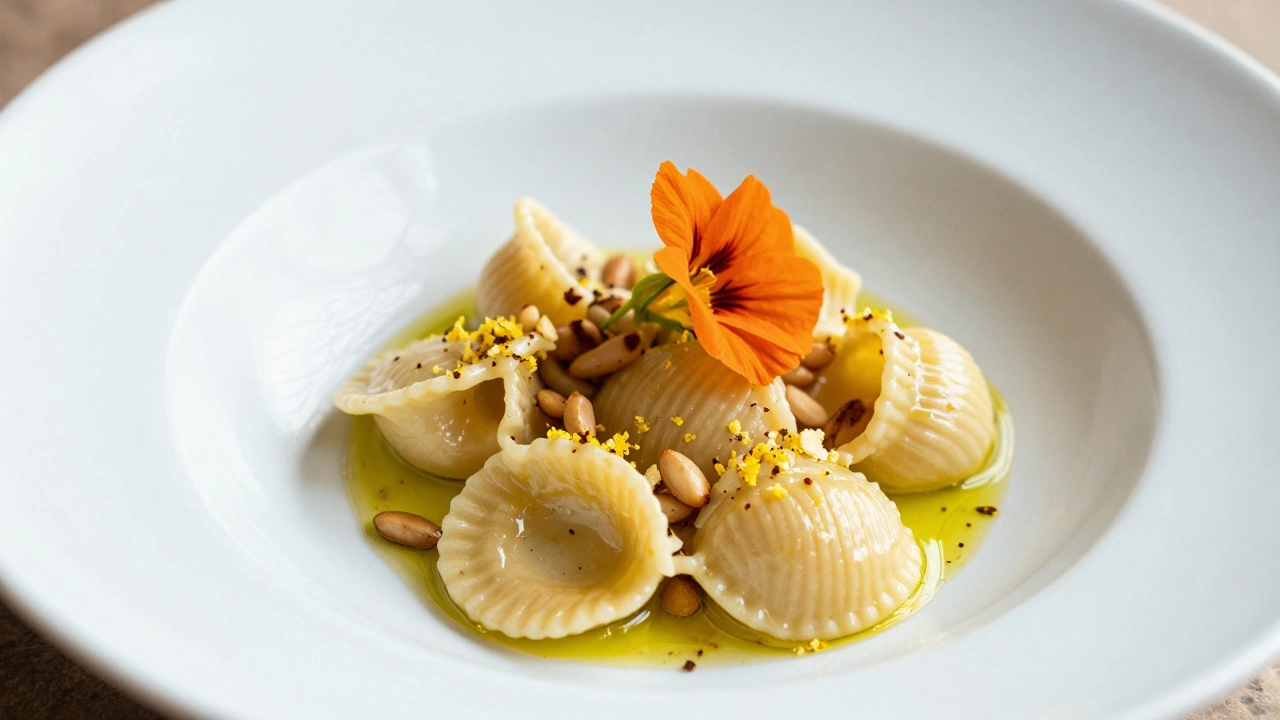 Orecchiette pasta with lemon zest, pine nuts, and an edible flower on a pale stoneware bowl.
