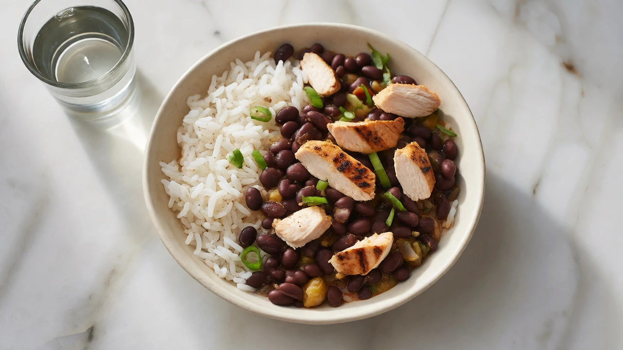 Top-down view of a burrito bowl with white rice, black beans, and grilled chicken.